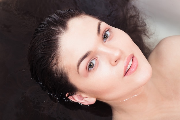 Jonge vrouw in de badkamer om haar onder water te spoelen