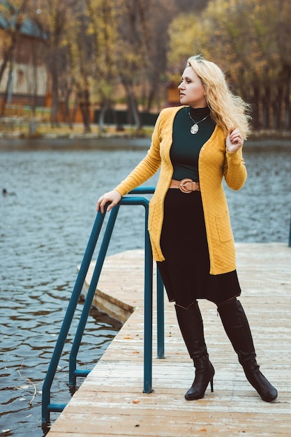 Jonge vrouw in de herfst op de pier kijkt weg