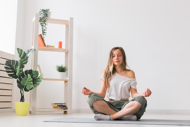 Jonge vrouw in de lotuspositie terwijl ze mediteert op mindfulness, oefent welzijn en zelfconcept