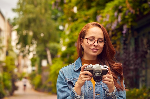 Jonge vrouw in de stad die foto maakt op digitale camera om op sociale media te posten