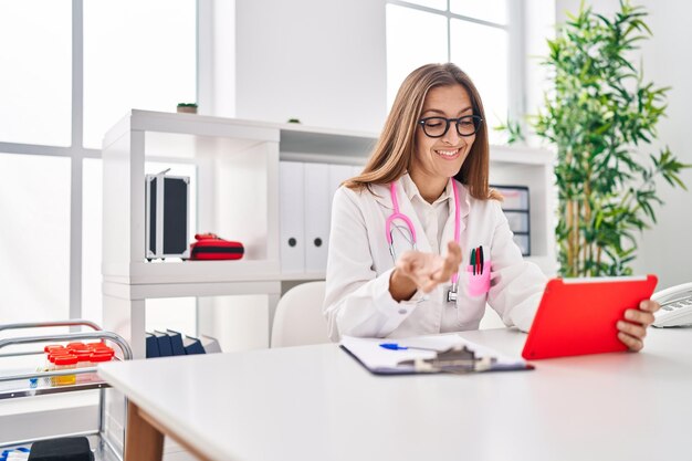 Jonge vrouw in doktersuniform met behulp van touchpad die in de kliniek werkt