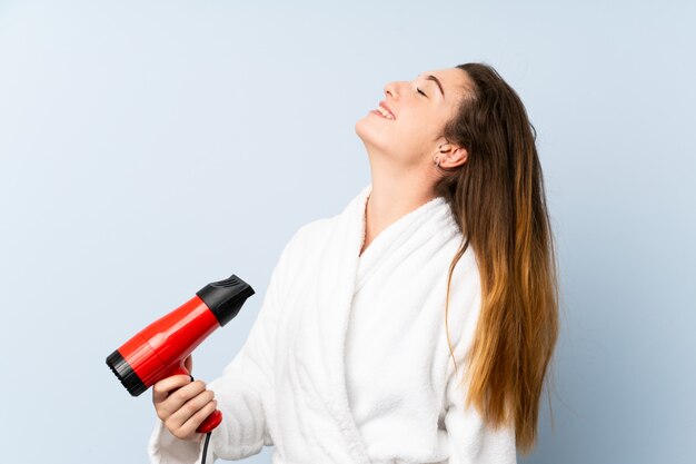 Jonge vrouw in een badjas met haardroger