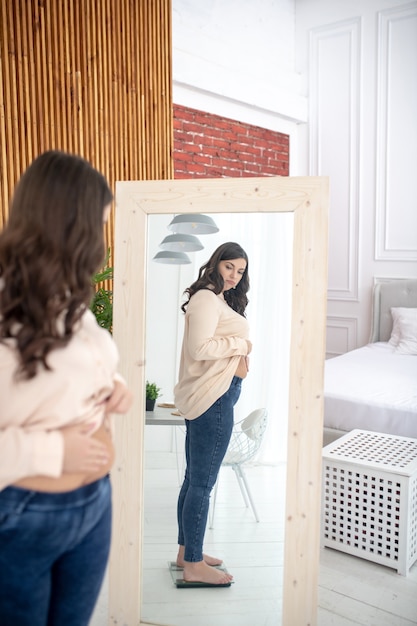 Jonge vrouw in een beige blouse die zich op vloerschalen bevindt