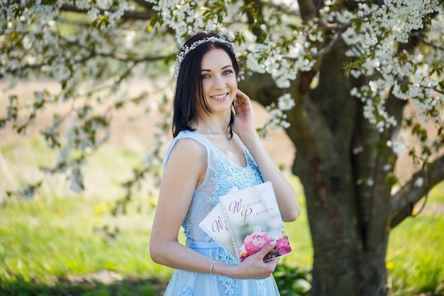 Jonge vrouw in een blauwe lange jurk houdt een huwelijkszweefvliegtuig in haar handen