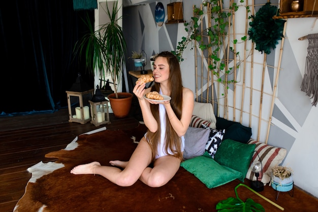 Jonge vrouw in een bodysuit croissants eten