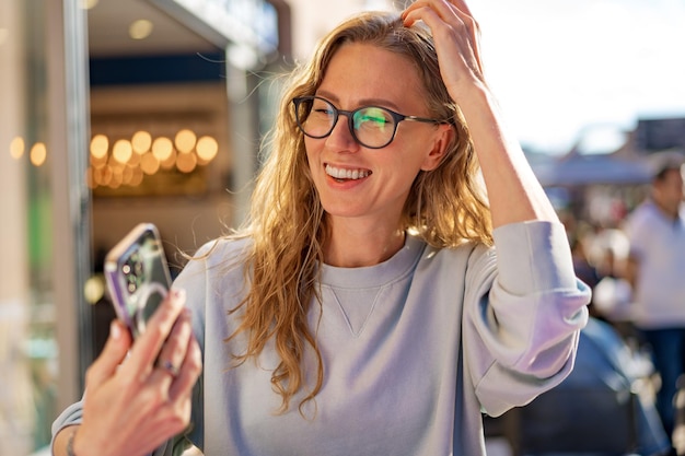 Jonge vrouw in een café leest een sms-bericht van haar mobiele telefoon