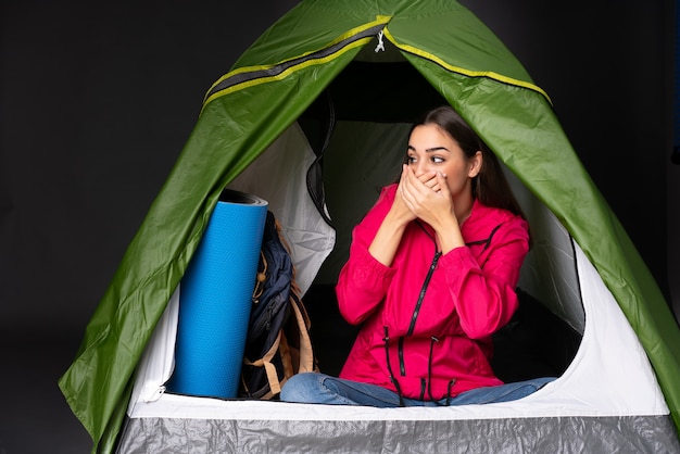 Foto jonge vrouw in een camping groene tent die mond en kijken naar de kant