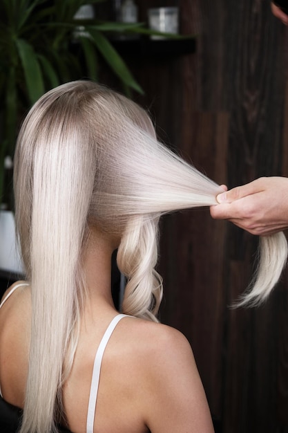 Jonge vrouw in een kapsalon verft haar haar blond en draait krullen