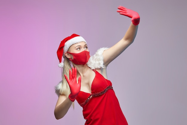 Jonge vrouw in een kerstmuts en gezichtsmasker voor Kerstmis