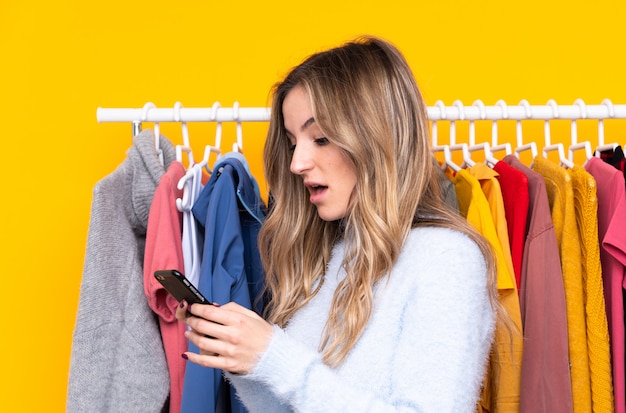 Jonge vrouw in een kledingwinkel met een mobiel