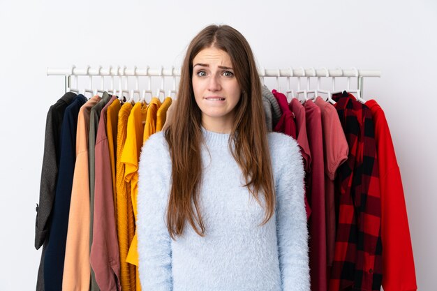 Jonge vrouw in een kledingwinkel met twijfels en met verwarren gezichtsuitdrukking