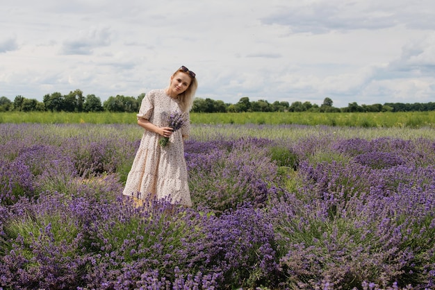 Jonge vrouw in een lavendelveld met een boeket lavendel op een zonnige dag