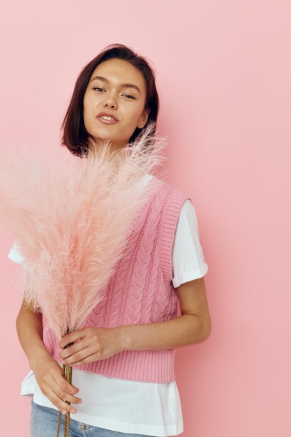 Jonge vrouw in een roze vest met veren in zijn handen geïsoleerde background