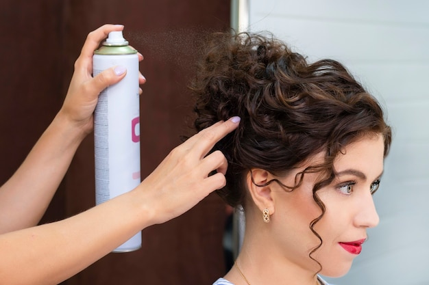 Jonge vrouw in een schoonheidssalon. Kapper maakt kapsel. Haarlak.