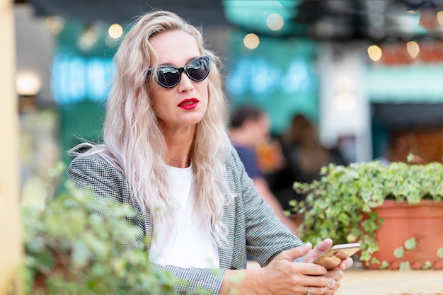 Jonge vrouw in een straatcafé met een telefoon.