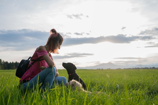 Jonge vrouw in een weiland met haar twee honden