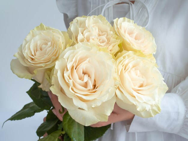 Jonge vrouw in een witte jurk met boeket bloemen op een witte achtergrond met kopieerruimte.