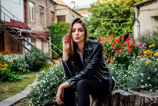 Jonge vrouw in een zwart lederen jas in de tuin