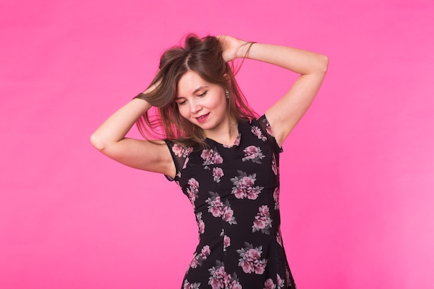 Jonge vrouw in elegante zomerjurk. Meisje poseren op een roze achtergrond.