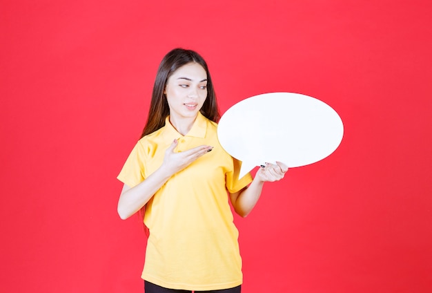 Jonge vrouw in geel shirt met een ovale infobord