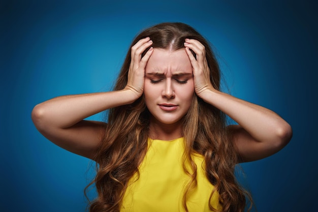 Jonge vrouw in gele t-shirt op blauwe achtergrond