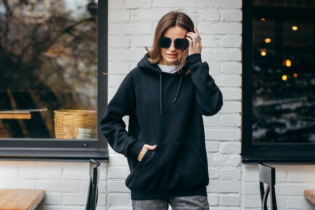 Jonge vrouw in glazen en zwarte hoodie