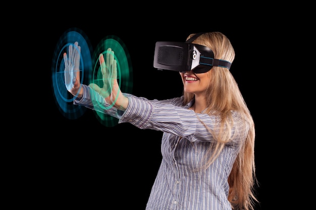 Jonge vrouw in grijs shirt met blond haar kijkend door de virtual reality-headset op zwarte achtergrond.