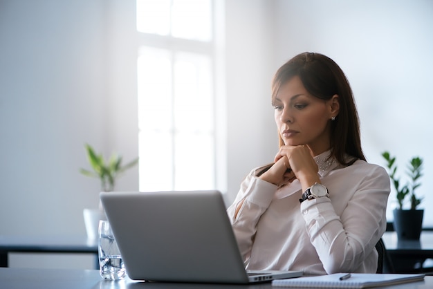 Jonge vrouw in het bureau dat met laptop werkt