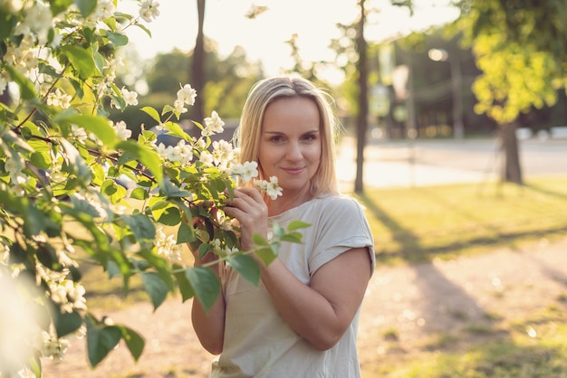 Jonge vrouw in het park op een zonnige dagtuin onder de bloeiende boom De regen van het lentebloemblaadje Concept van de lente gelukkige vrede in de wereldvrede en gelukharmonie