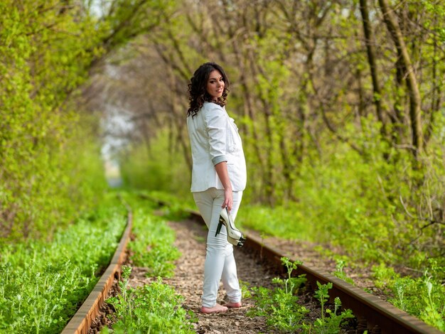 Jonge vrouw in het wit op de rails in de natuur