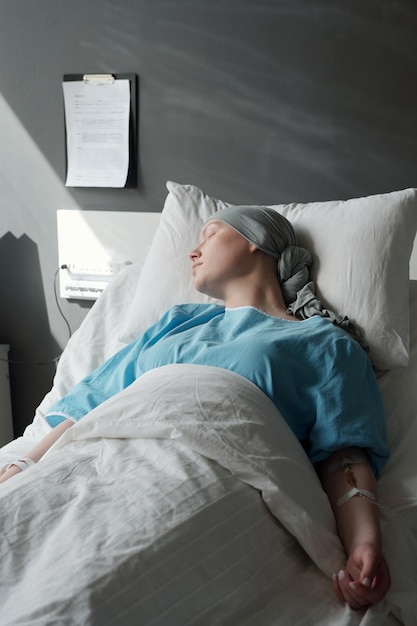 Jonge vrouw in hoofddoek en blauw shirt in bed liggen en slapen