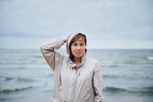 Jonge vrouw in jas in de buurt van zee