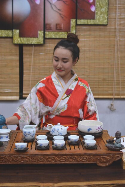 Jonge vrouw in kimono met thee op tafel die thuis zit