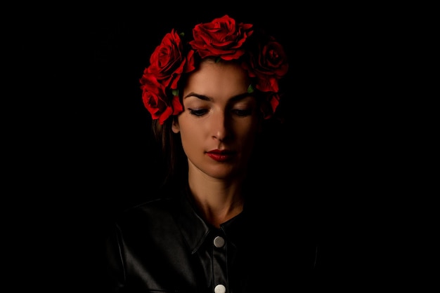 Jonge vrouw in krans met rode bloemen op zwarte achtergrond