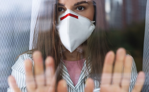 Jonge vrouw in medisch masker verblijf thuis isolatie voor zelfquarantaine.