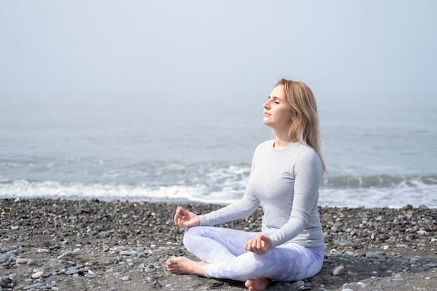 Jonge vrouw in meditatie pose op het strand