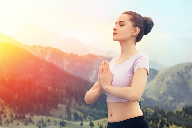 Jonge vrouw in namaskar Outdoor yoga in de bergen