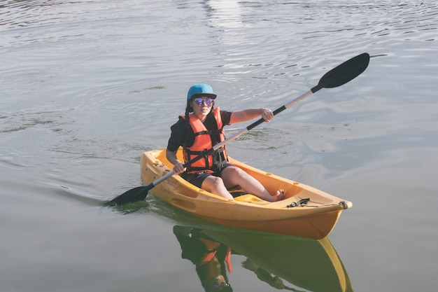 Foto jonge vrouw in oranje reddingsvesten die op een meer kayaking.