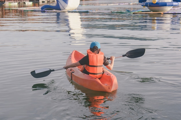 Jonge vrouw in oranje reddingsvesten die op een meer kayaking.