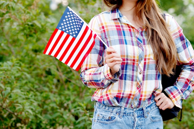 Jonge vrouw in plaid shirt en korte broek met amerikaanse vlag