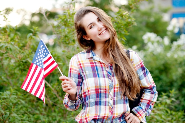 Jonge vrouw in plaid shirt en korte broek met Amerikaanse vlag