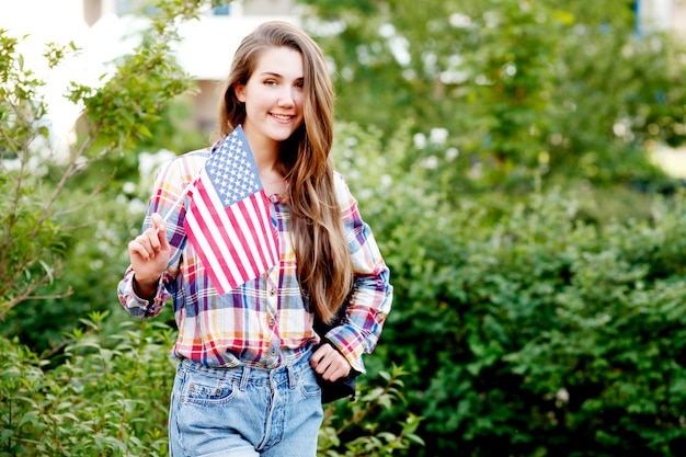 Jonge vrouw in plaid shirt en korte broek met Amerikaanse vlag