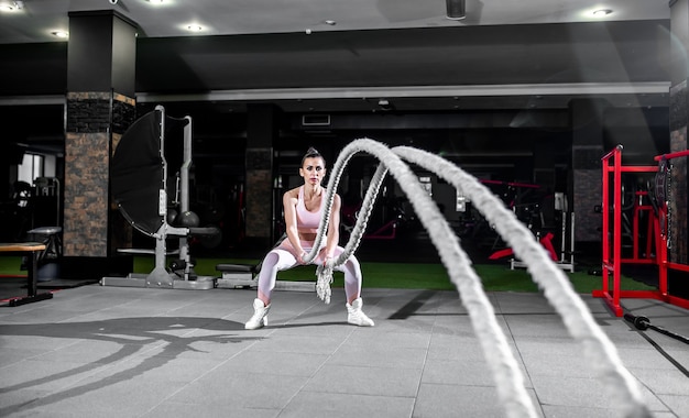 Jonge vrouw in professionele sportschool oefeningen met touw te bestrijden.