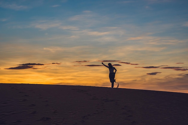 Jonge vrouw in rad zandwoestijn bij zonsondergang