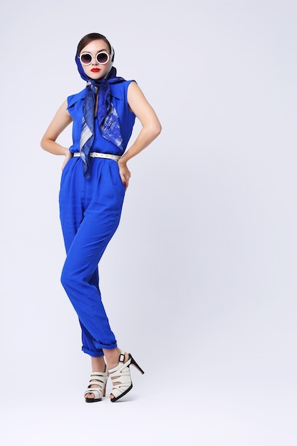 Jonge vrouw in retro stijl met zonnebril en zijden sjaal en blauwe overall. Jaren zestig stijl mode retro vrouw.