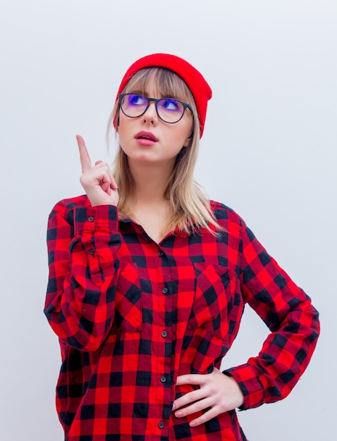 Jonge vrouw in rode shirt en hoed met een bril