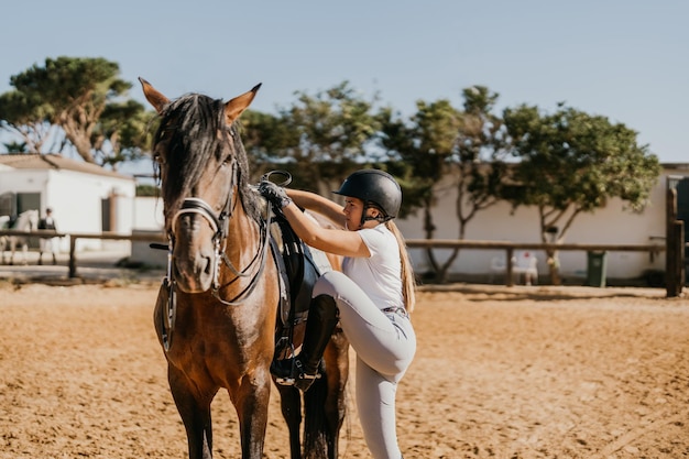 Jonge vrouw in ruiterkleding die op een paard stapt