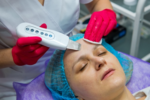 Jonge vrouw in schoonheidssalon doen echografie peeling en gezichtsreiniging procedure. detailopname.