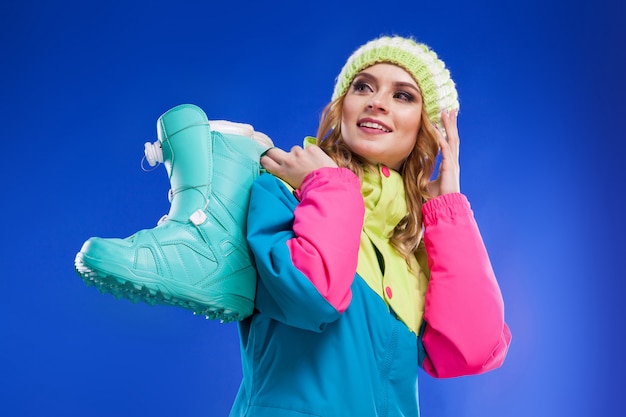 Jonge vrouw in ski pak houden blauwe skischoenen