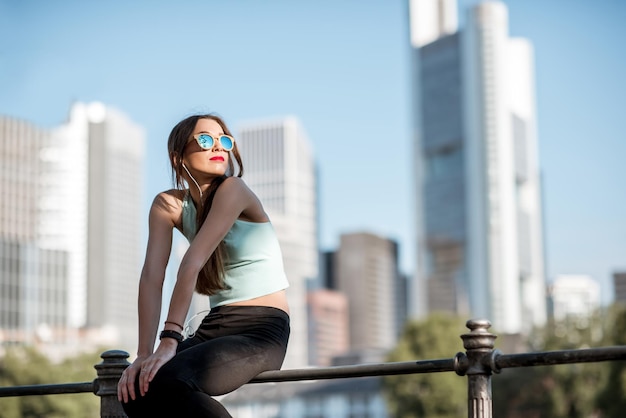 Jonge vrouw in sportkleding die op het hek rust tijdens de ochtendoefening in de stad Frankfurt